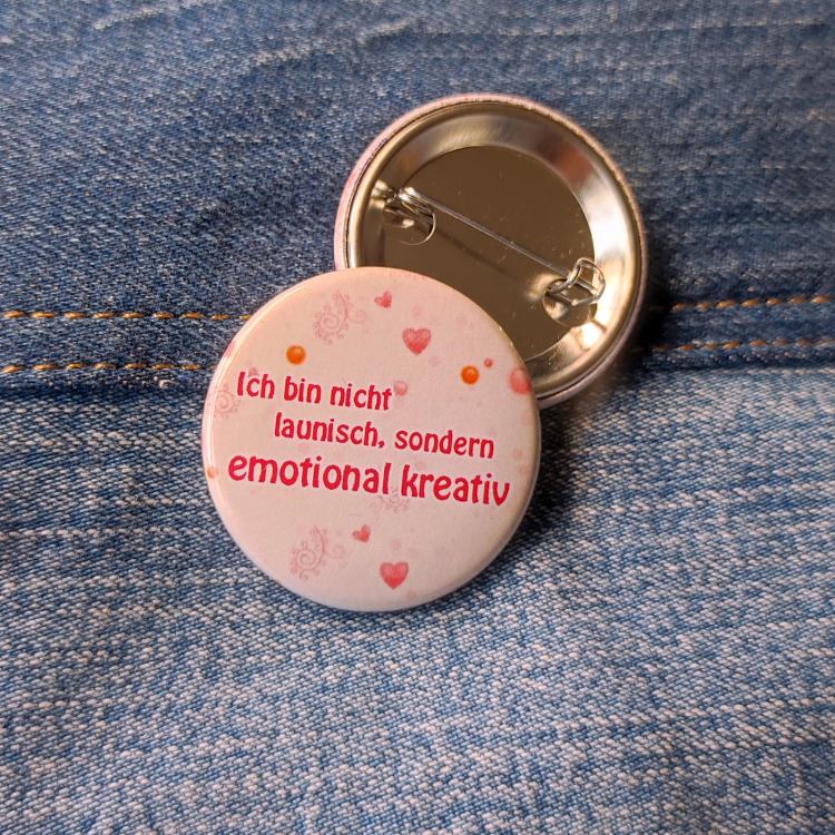 Ansteckbutton Ich bin nicht launisch, sondern emotional kreativ auf Jeans mit Rückseite